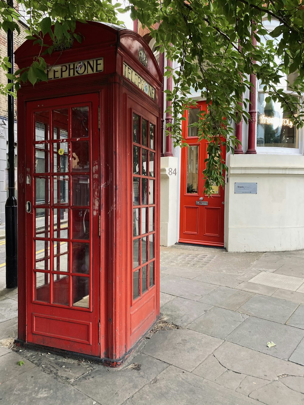 Eine rote Telefonzelle, die am Straßenrand sitzt