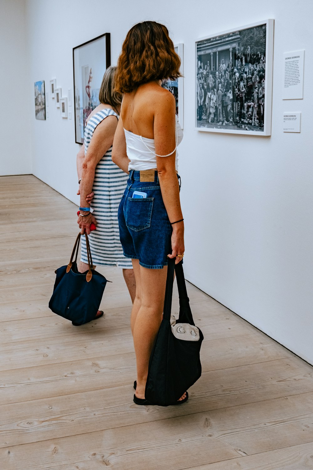 Una donna in canottiera bianca e pantaloncini di jeans che guarda le immagini su un muro