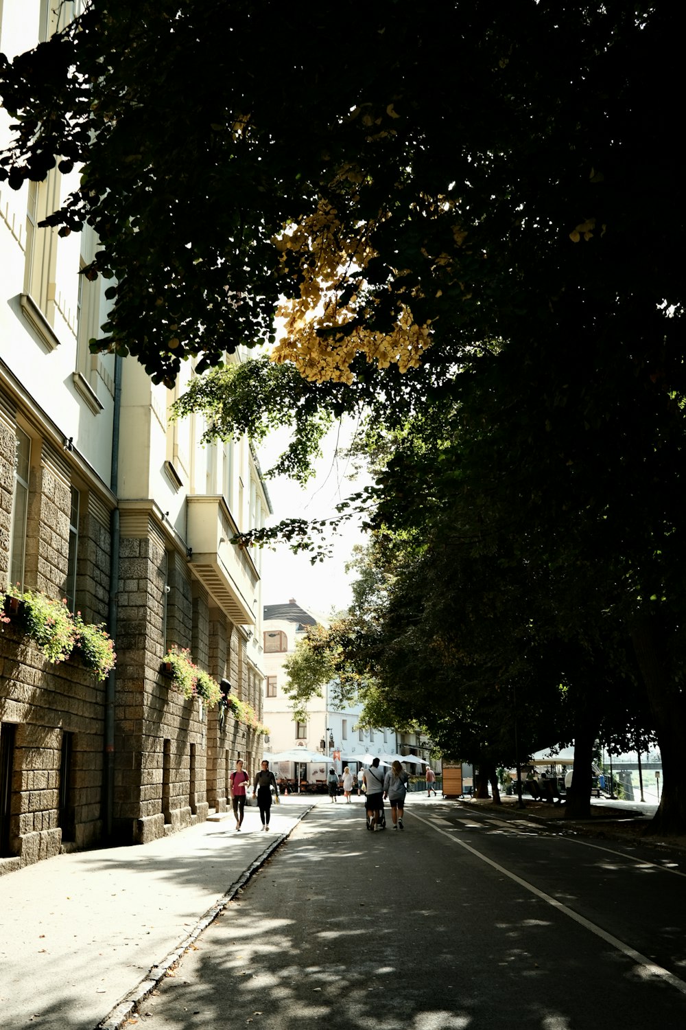 two people walking down a street next to tall buildings