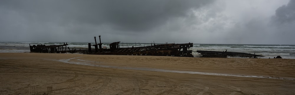 a boat sitting on top of a sandy beach next to the ocean