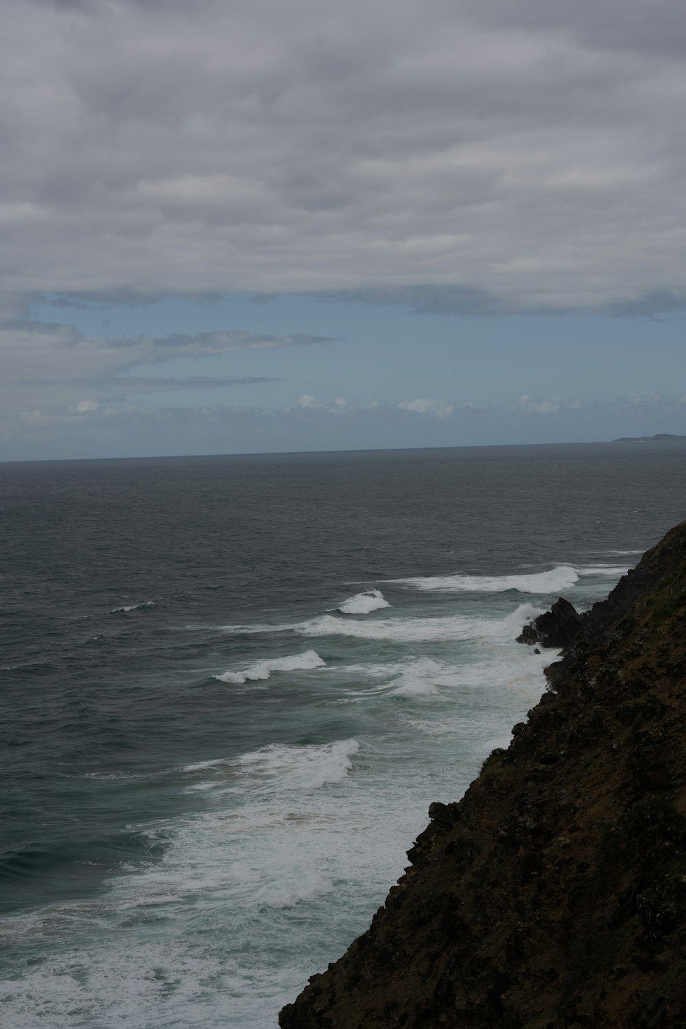 eine Person, die auf einer Klippe mit Blick auf den Ozean steht