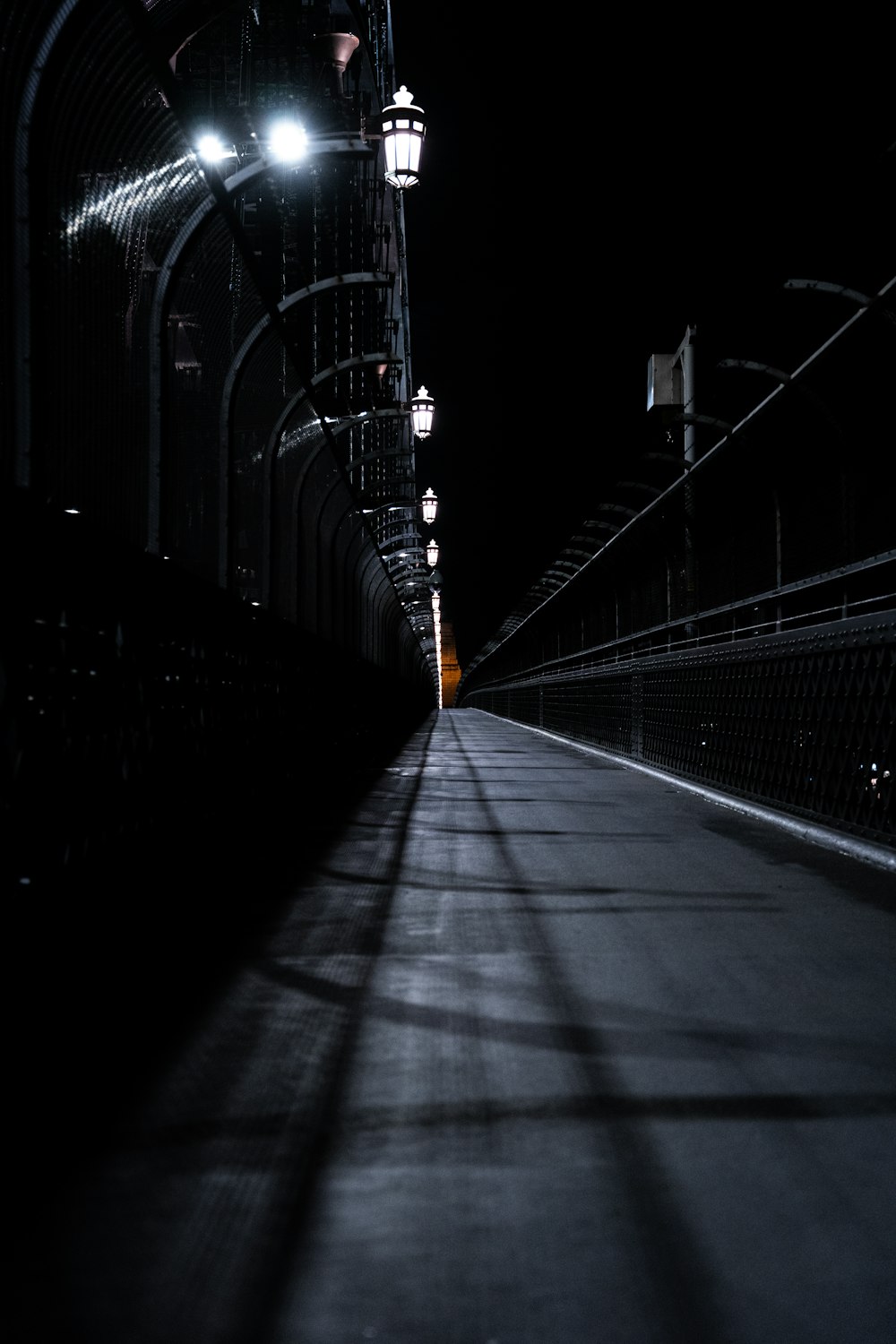 une longue passerelle sombre avec des lampadaires de chaque côté