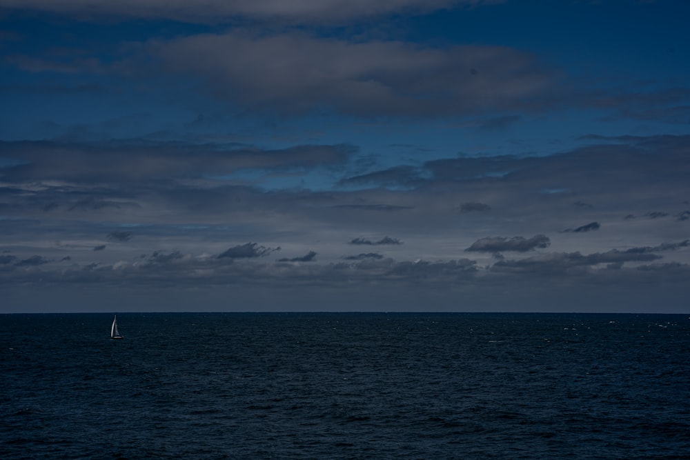 um veleiro no meio do oceano sob um céu nublado