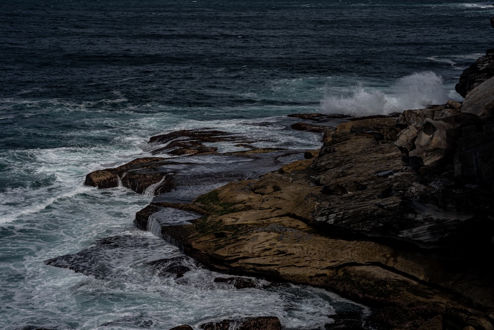 Una persona in piedi sulla cima di una scogliera vicino all'oceano