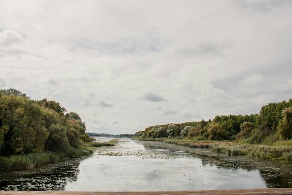 Reeds along a river into the lake — An aerial view of a green field with a lake in the background