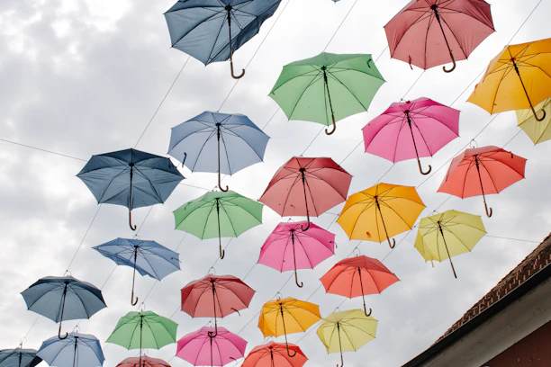 Brightly colored umbrellas hanging in a cozy shop window on a cloudy day.