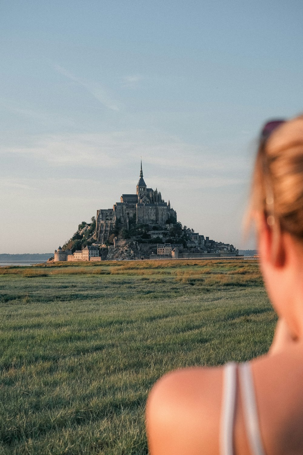 a woman standing in a field looking at a castle