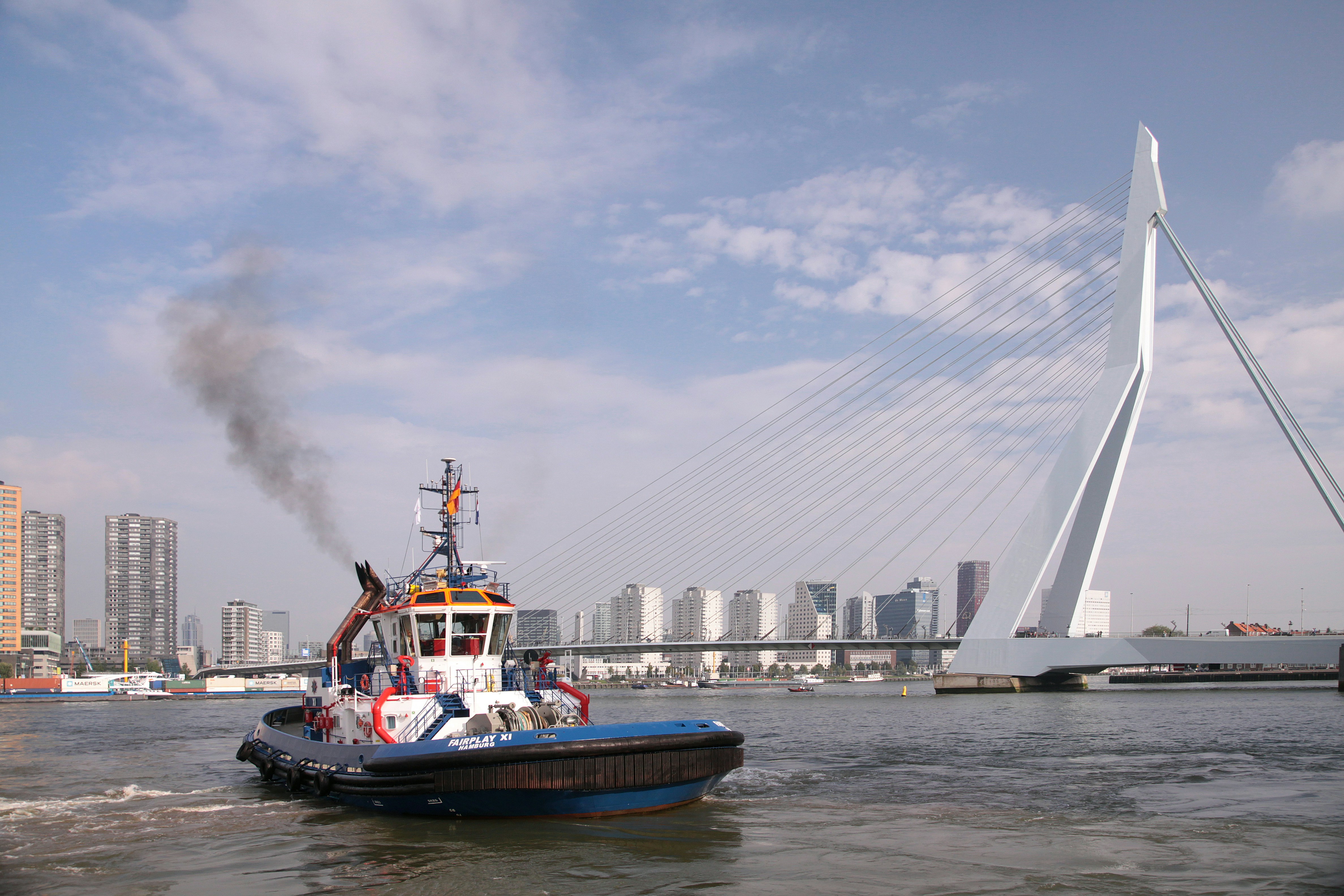a tug boat in the water with a bridge in the background