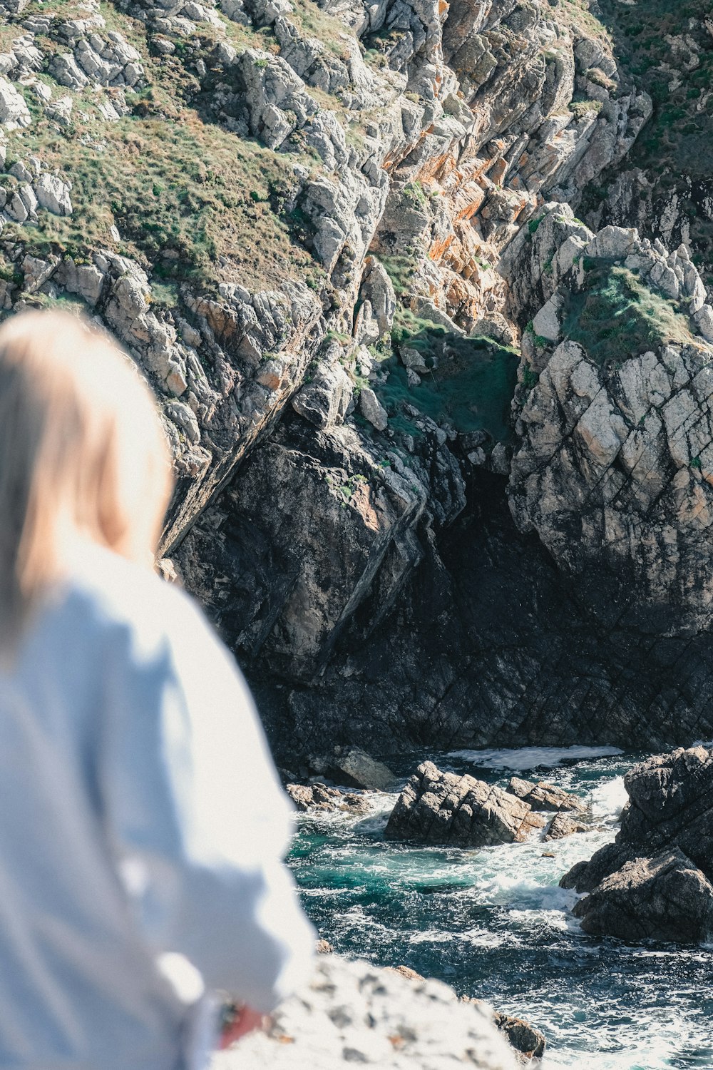 a woman standing on a rocky beach next to a body of water