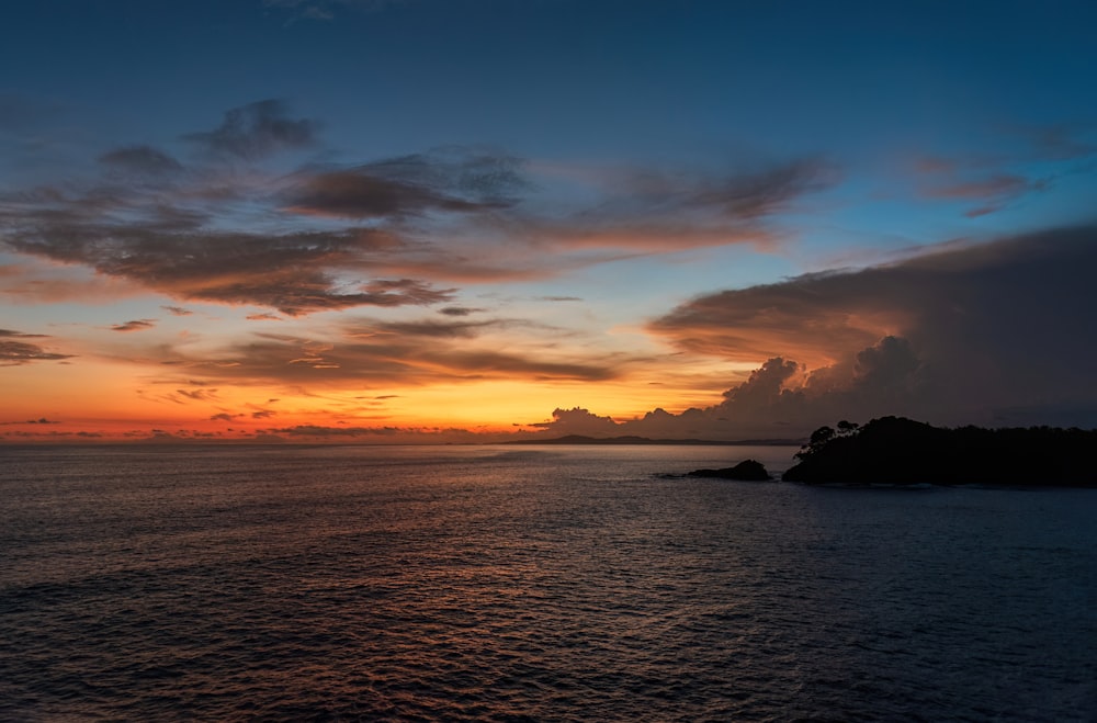 a sunset over a body of water with clouds in the sky