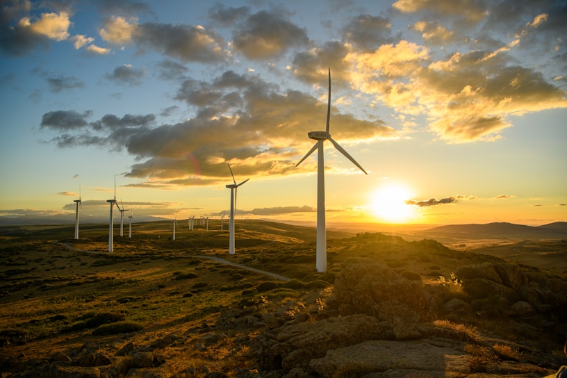 a group of windmills on a hill at sunset