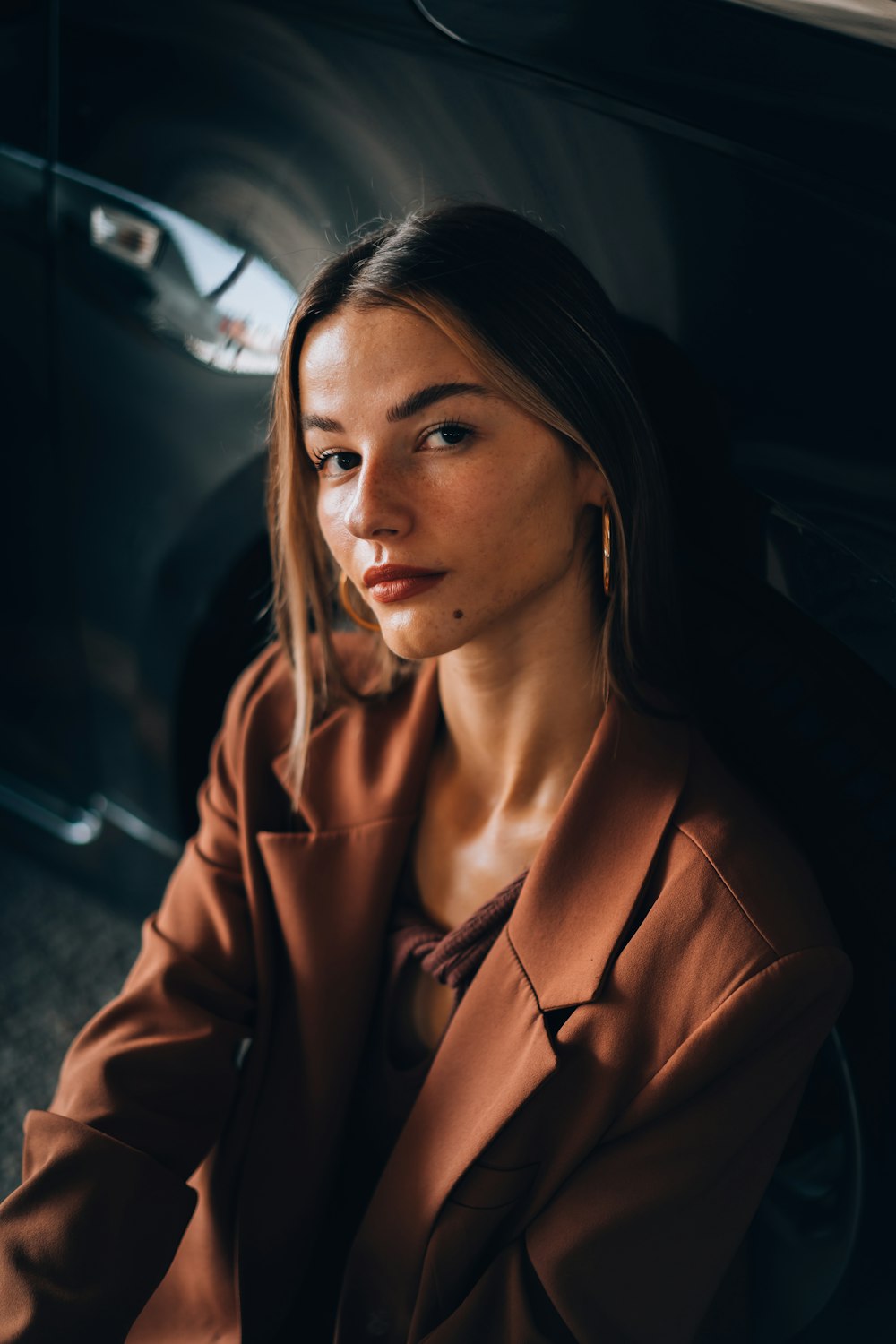 a woman sitting in front of a black car