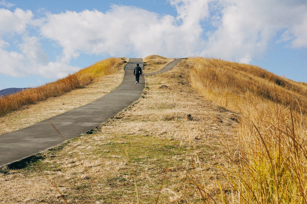 a person walking up a hill with a sky background