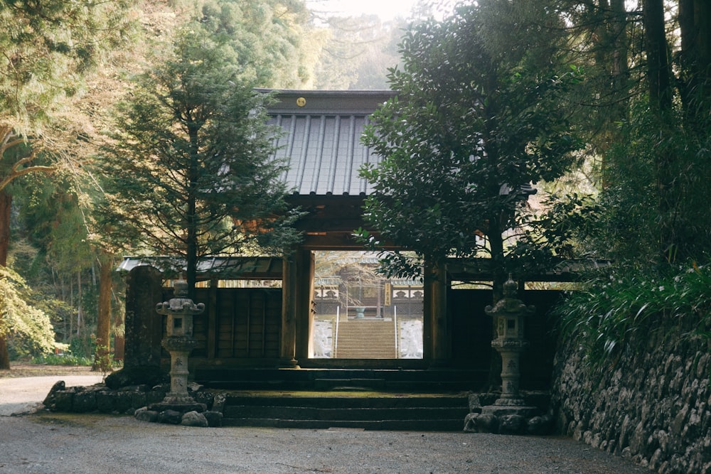 a stone building with a gate in the middle of a forest