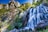A scenic mountain waterfall surrounded by lush greenery under a clear sky.