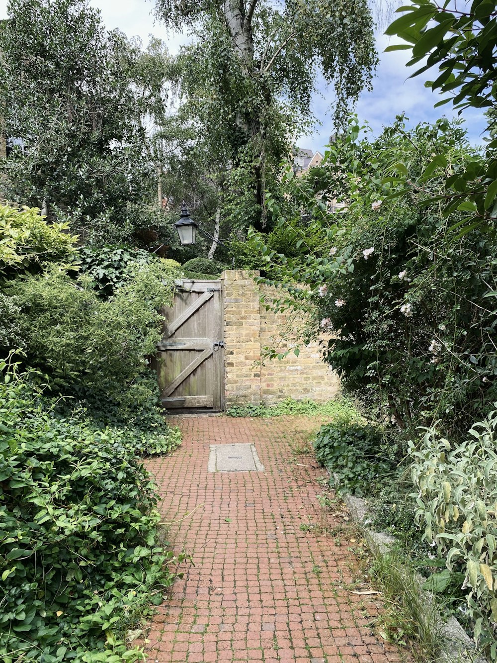 a brick path leading to a wooden gate