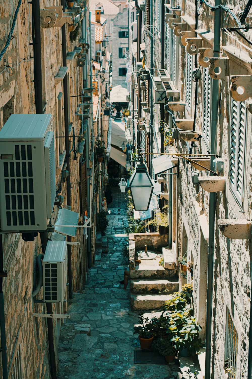 a narrow alleyway with stone buildings and plants