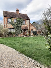 A charming old UK house with worn bricks and overgrown garden, ready for renovation.