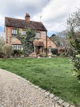 A charming old UK house with worn bricks and overgrown garden, ready for renovation.