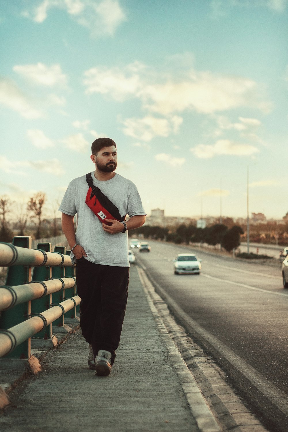 a man walking down a sidewalk next to a street