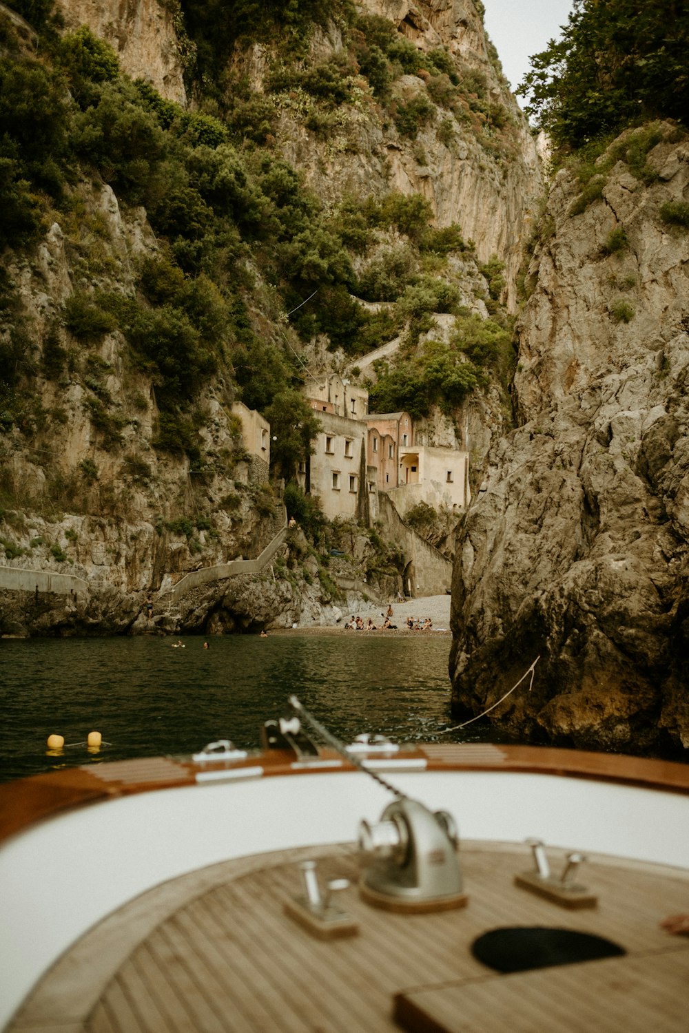a boat traveling down a river next to a rocky cliff