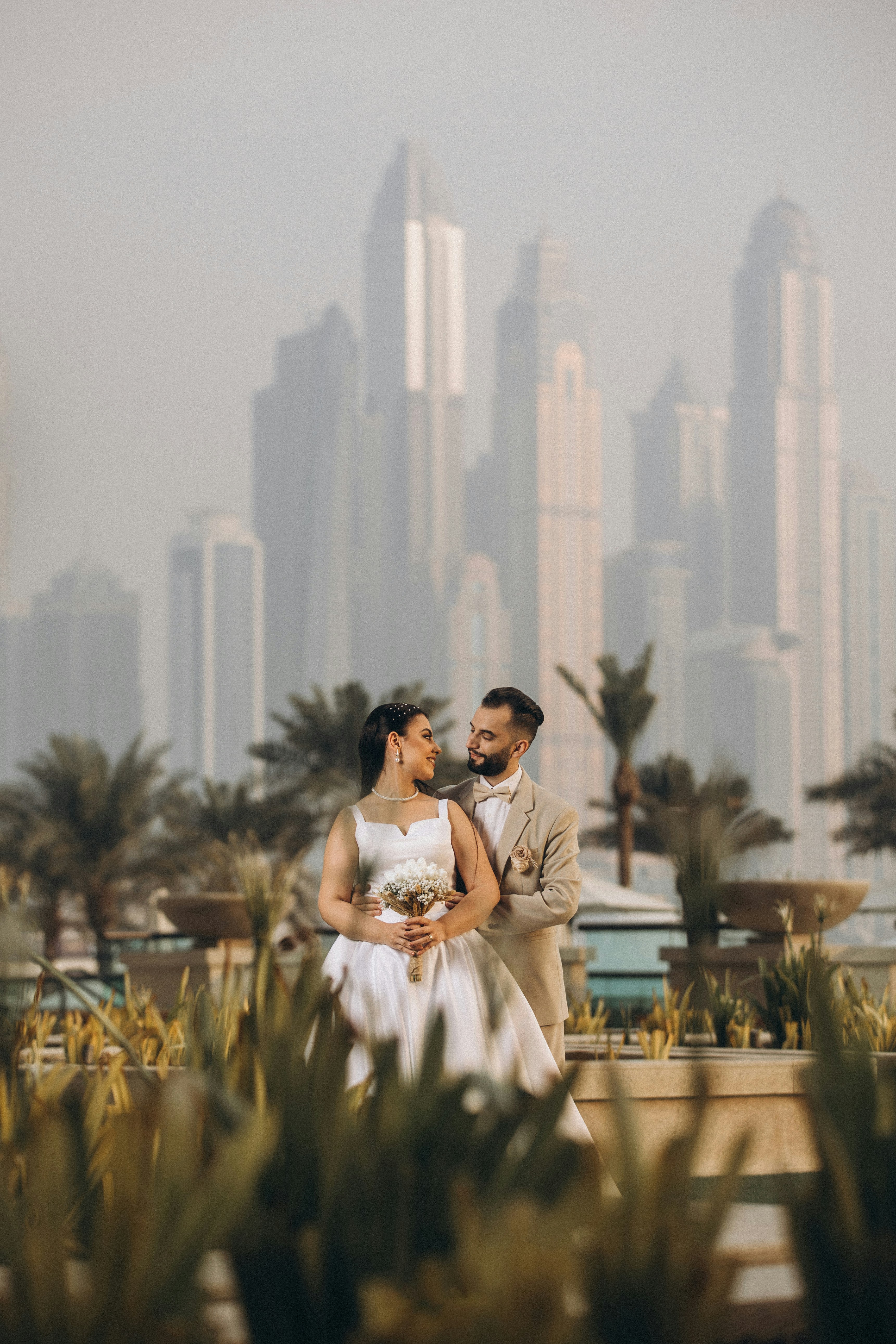 a bride and groom standing in front of a city skyline