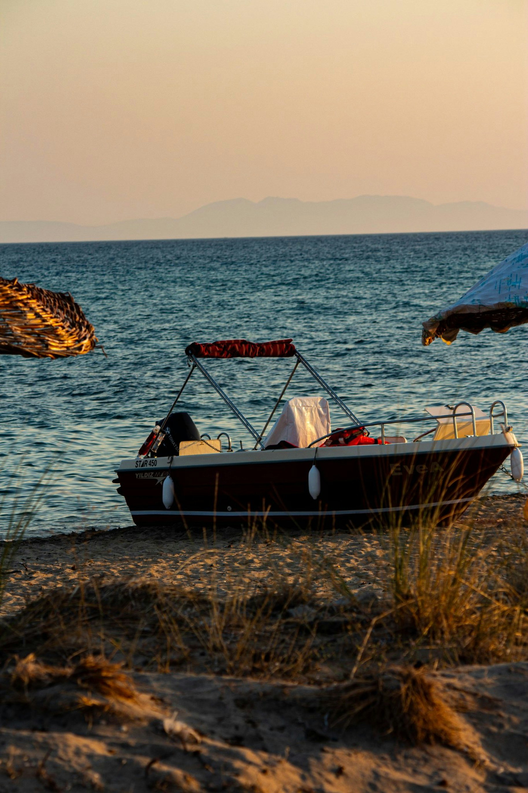 a-boat-on-the-beach-with-an-umbrella-in-the-background-TCVyIQCJoZo