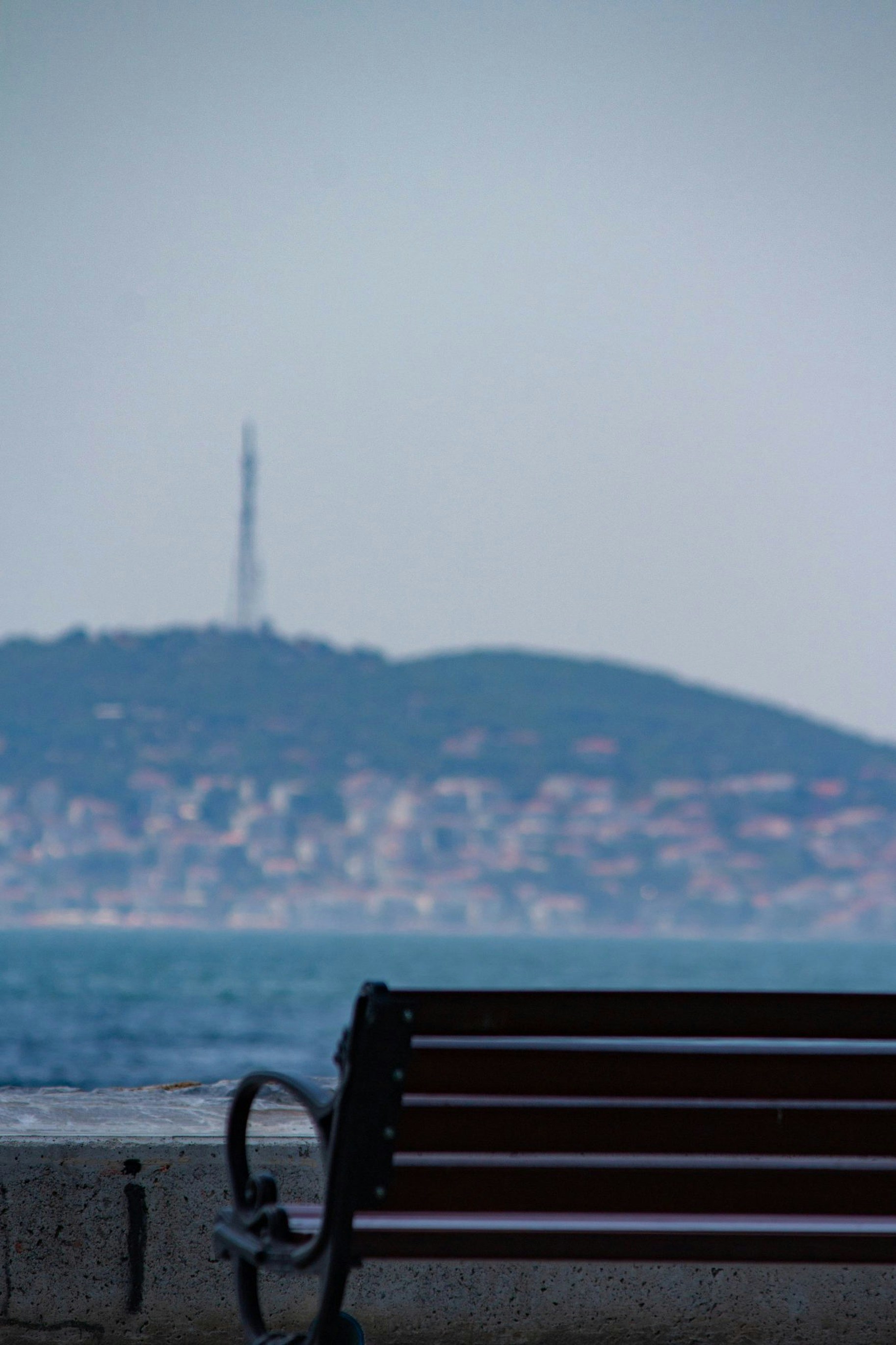 a-bench-overlooking-a-body-of-water-with-a-hill-in-the-background-vBePIyPtyRY