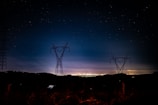 Night view of electrical grid towers lit up, showcasing power network maintenance.