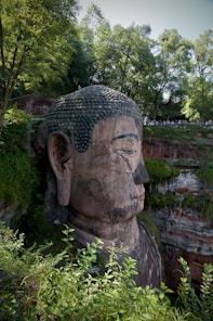 a large buddha statue sitting in the middle of a forest
