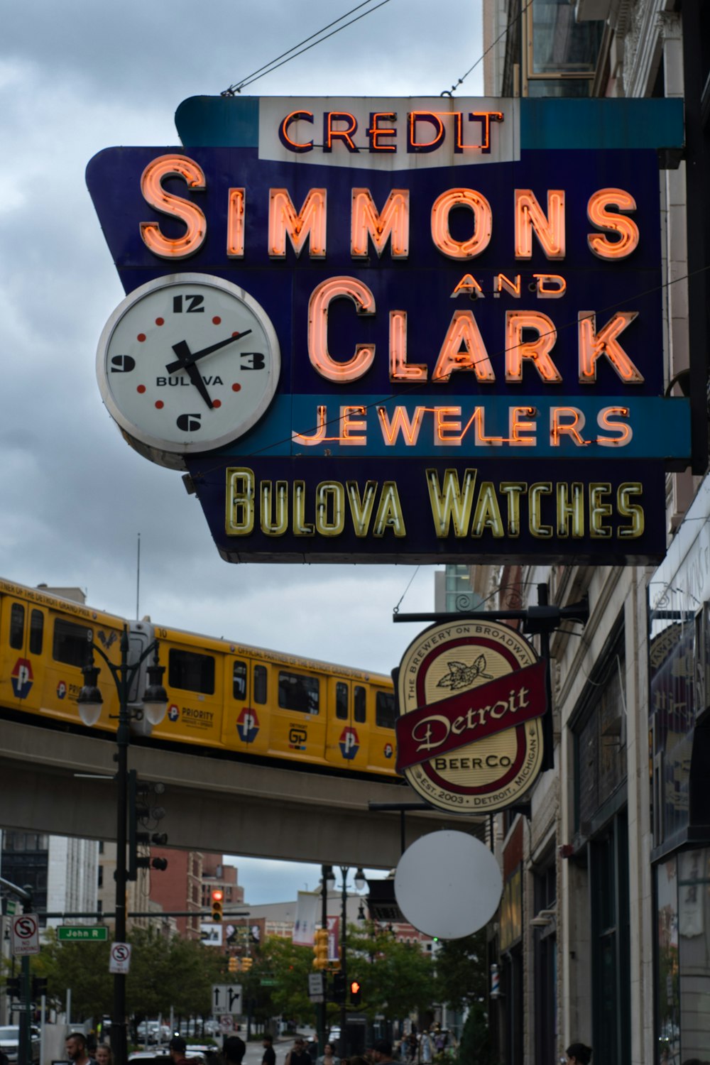 a neon sign for a jewelry store with a train in the background