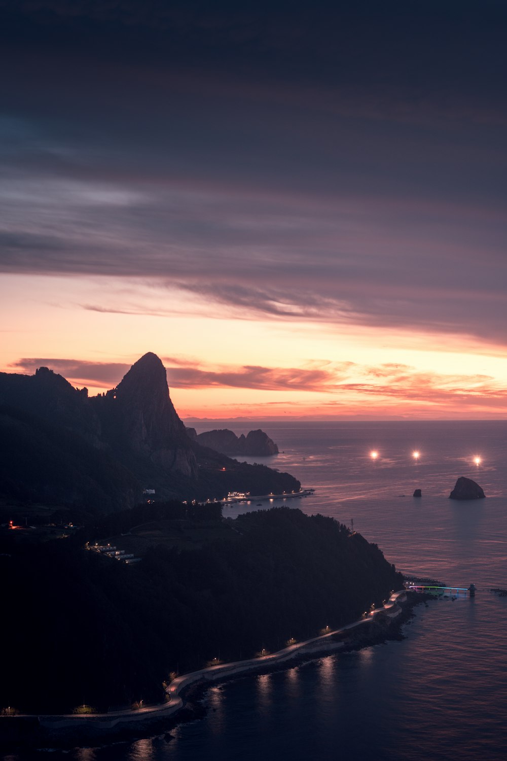 the sun is setting over the ocean with a mountain in the background