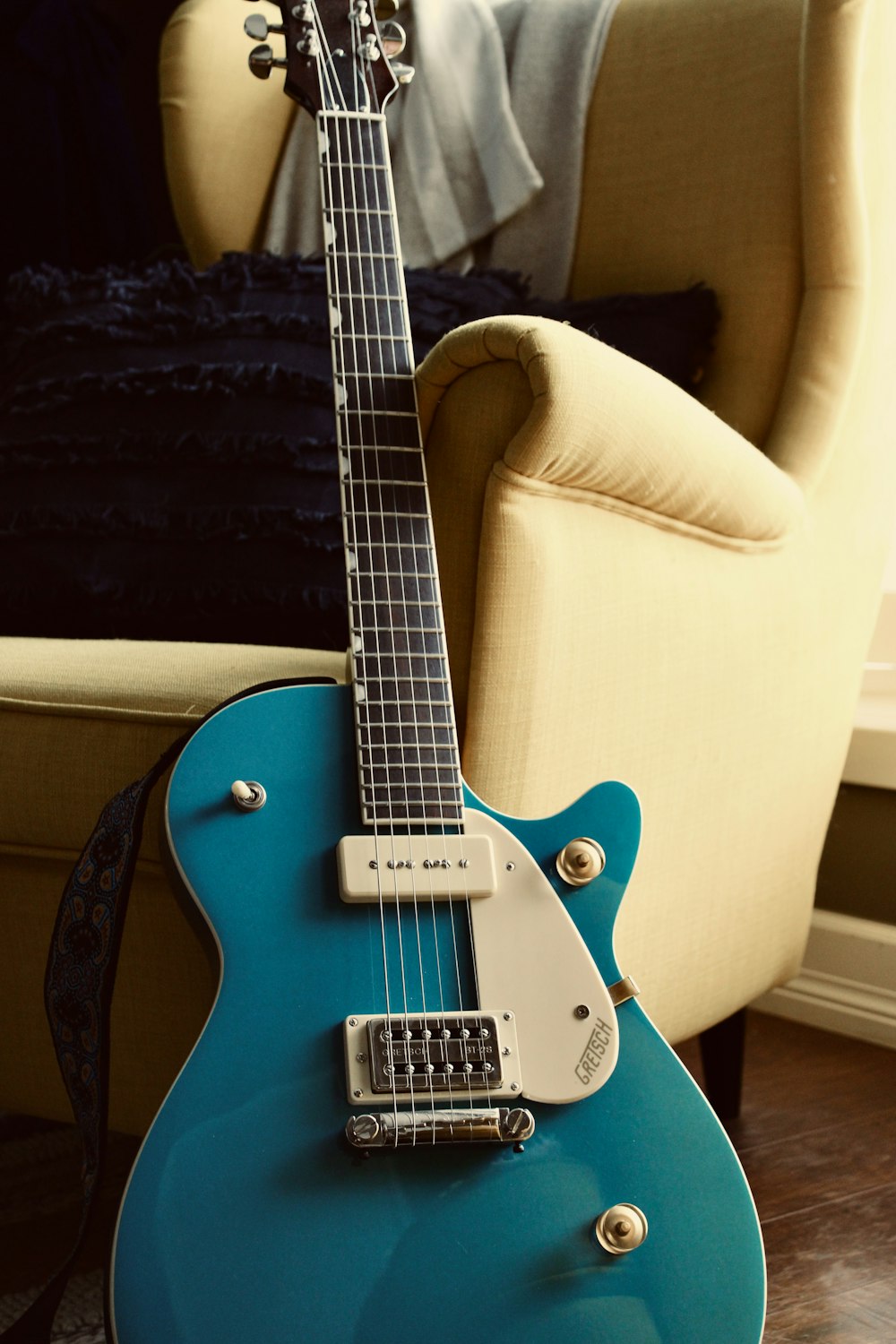 a blue guitar sitting on top of a hard wood floor