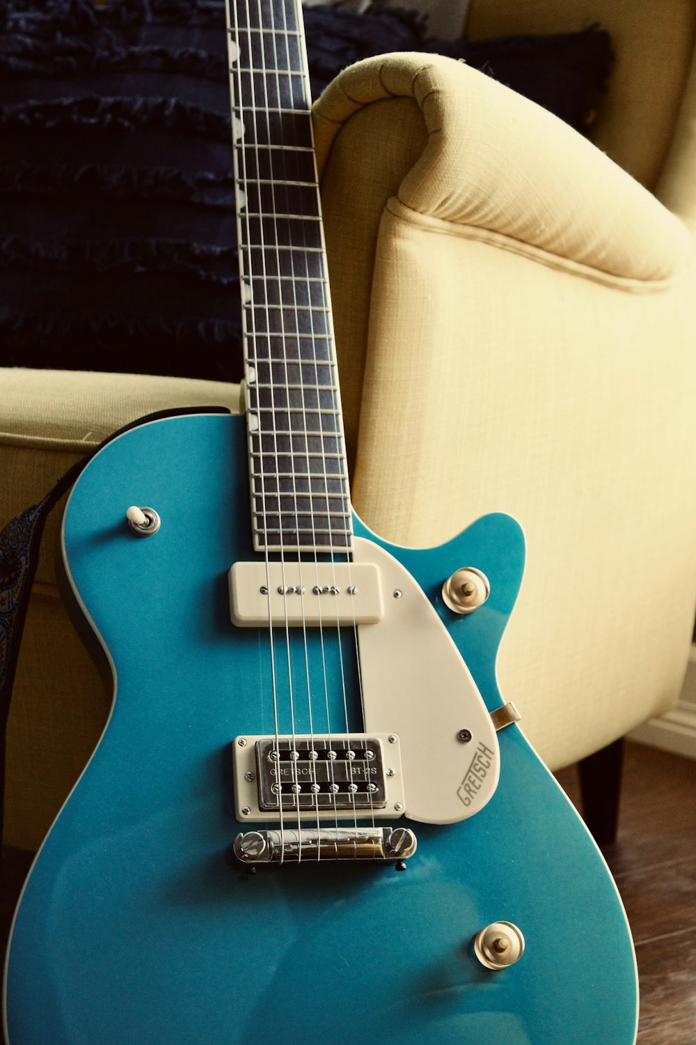 a blue guitar sitting on top of a hard wood floor