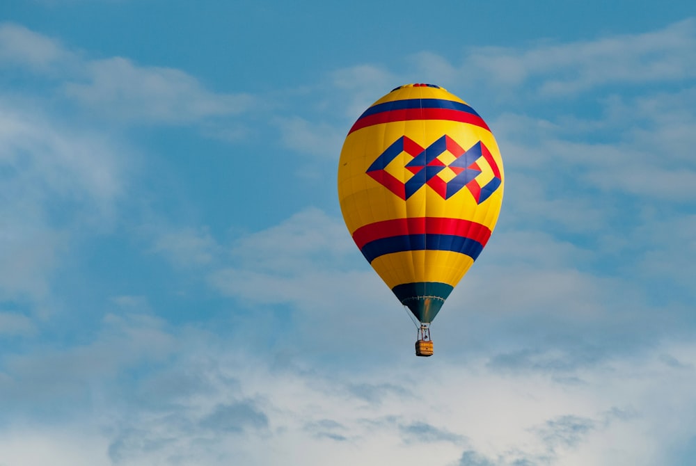 a colorful hot air balloon flying through a cloudy blue sky