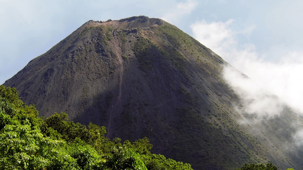 a very tall mountain surrounded by trees and clouds