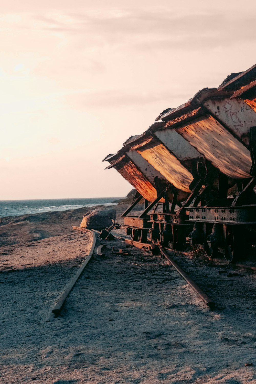 a rusted train car sitting on top of a sandy beach