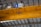 A drone is flying indoors near a large yellow overhead crane with a visible signage indicating 32t. The ceiling structure features metal beams and industrial lighting.