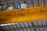A drone is flying indoors near a large yellow overhead crane with a visible signage indicating 32t. The ceiling structure features metal beams and industrial lighting.