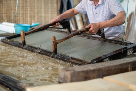 Close-up of hands shaping recycled paper pulp into sustainable packaging forms.