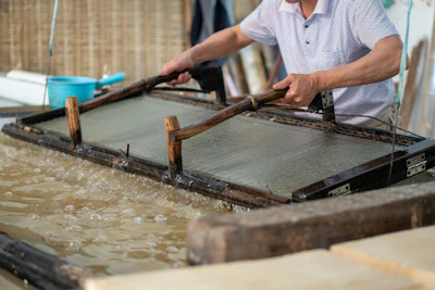 Artisan hands shaping bagasse pulp in a clean, modern Indian workshop.