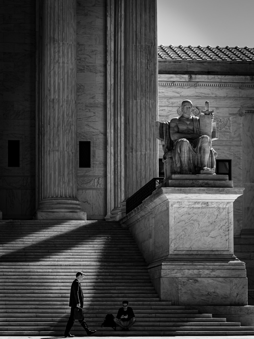 a black and white photo of a man walking up stairs