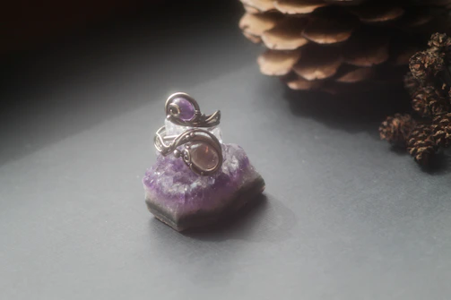 Elegant steel ring featuring a polished amethyst stone, softly lit on rustic wooden surface.