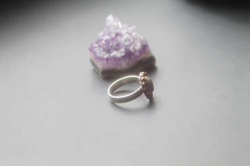 Handcrafted ring with a raw natural crystal set in smooth steel band, close-up detail.