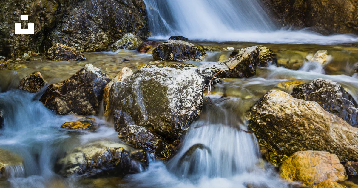 A small waterfall flowing over rocks into a river photo – Free Nature ...