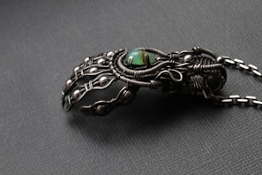 Close-up of a wire-wrapped steampunk pendant with antique watch gears and a deep blue stone, displayed on a velvet cloth.