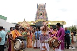 A colorful procession with traditional music and dancers outside the temple gates.