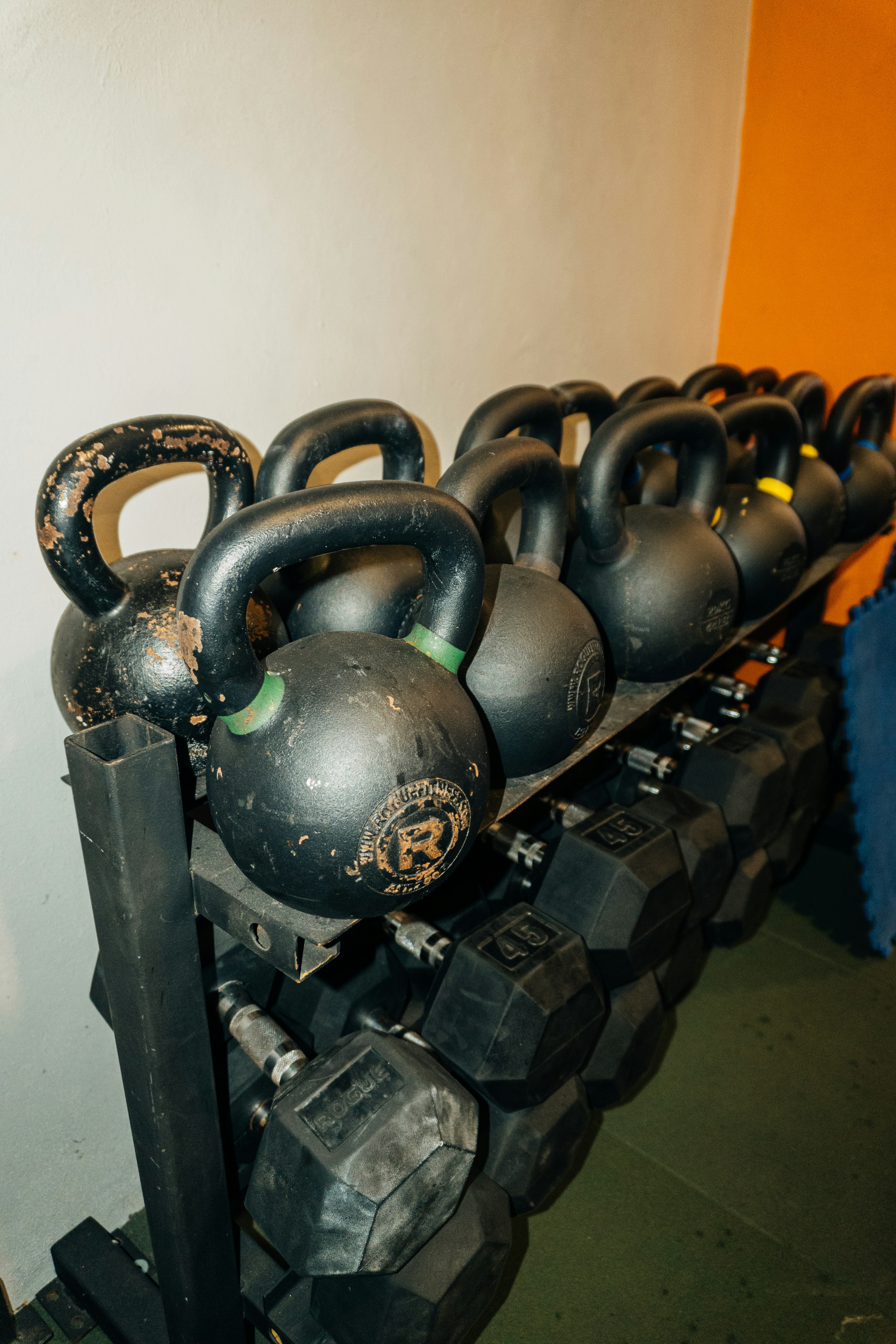 Elegant strength training equipment — dumbbells and kettlebells arranged on a clean home gym floor