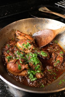 a pan filled with meat and vegetables on top of a stove