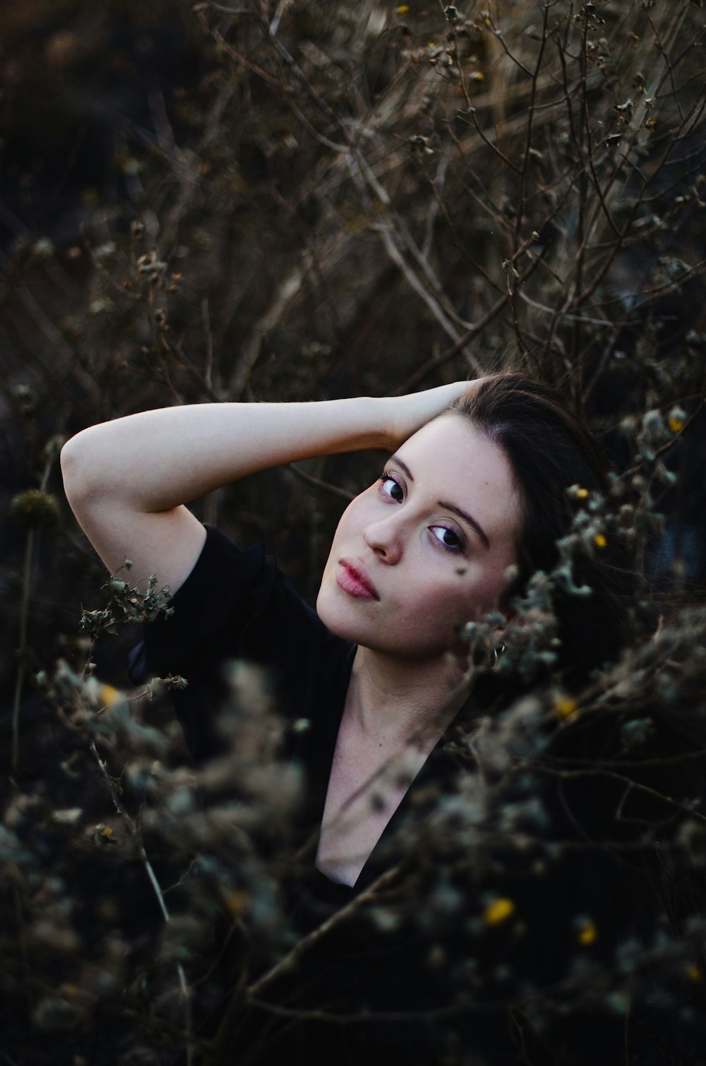 a woman standing in a bush with her hands on her head